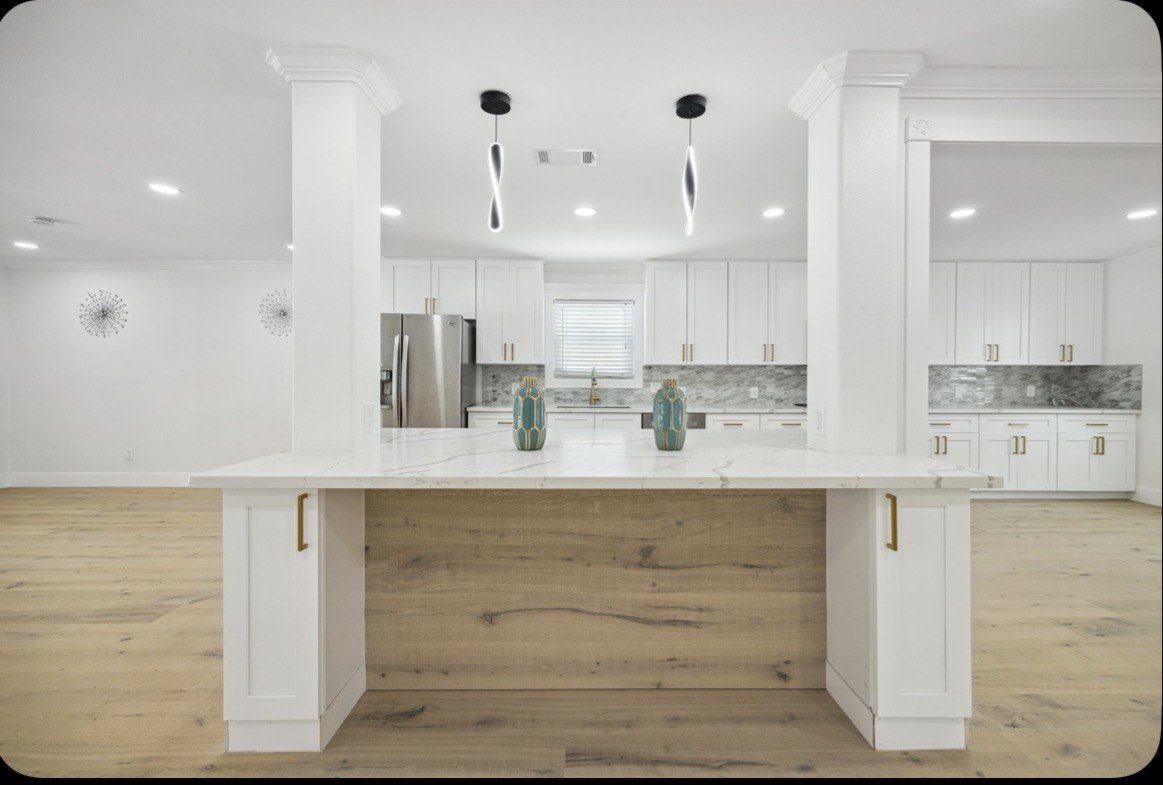 Completed open-concept kitchen renovation with large island, white cabinetry and wood-look flooring