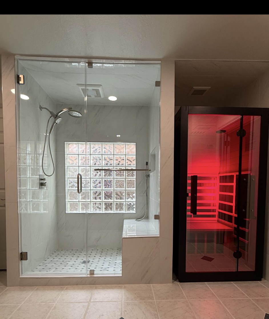 Completed bathroom renovation with frameless walk-in shower and red infrared sauna