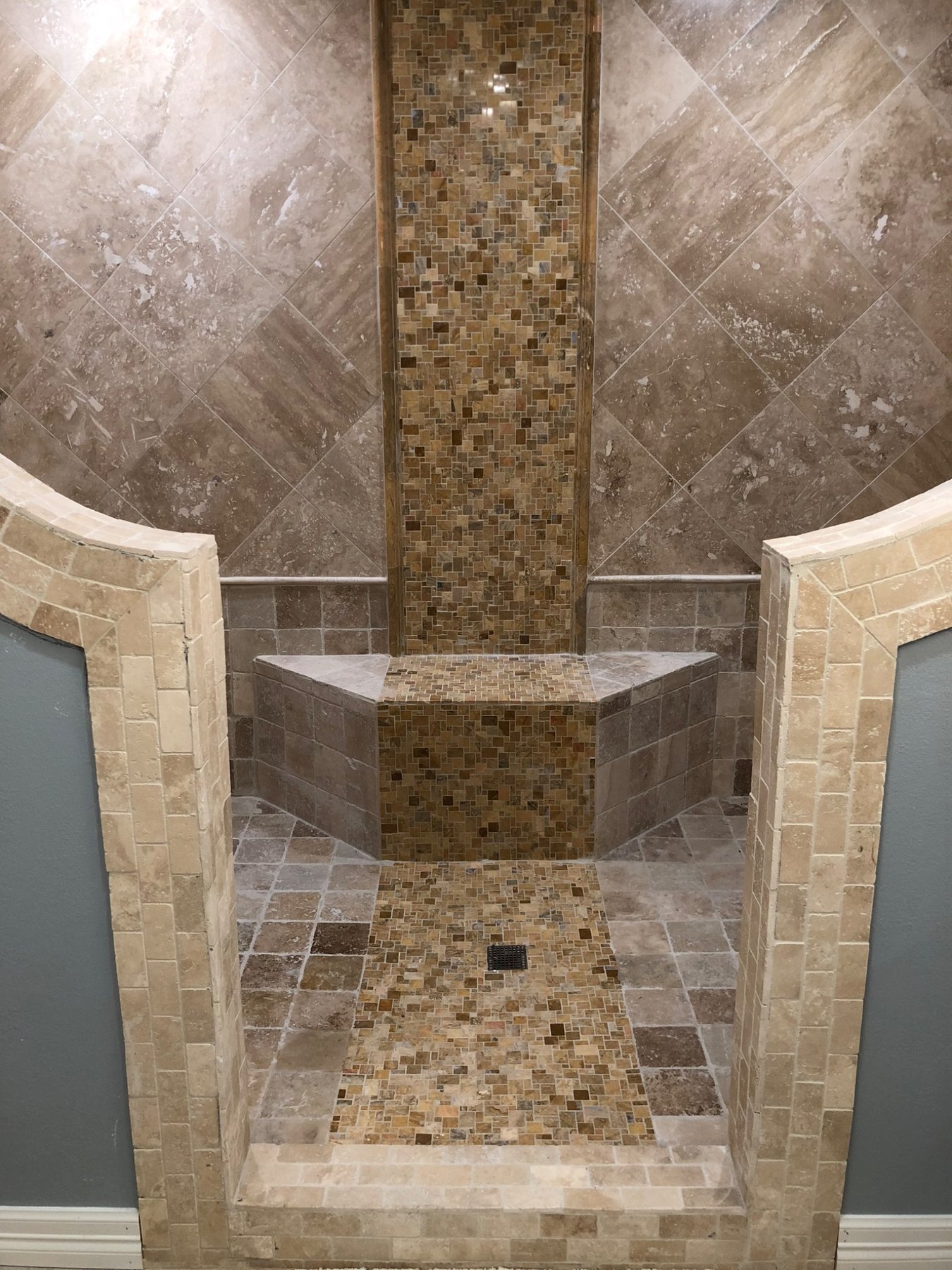 Traditional custom tiled shower with bench and stone accents