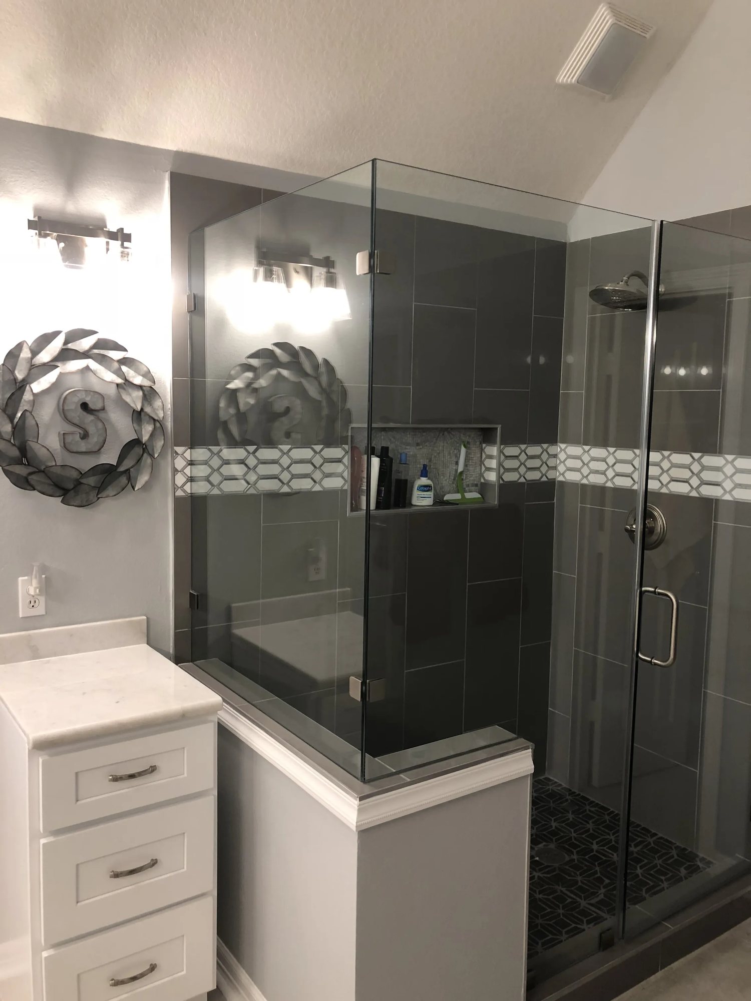 Modern gray tile walk-in shower with frameless glass and built-in niche