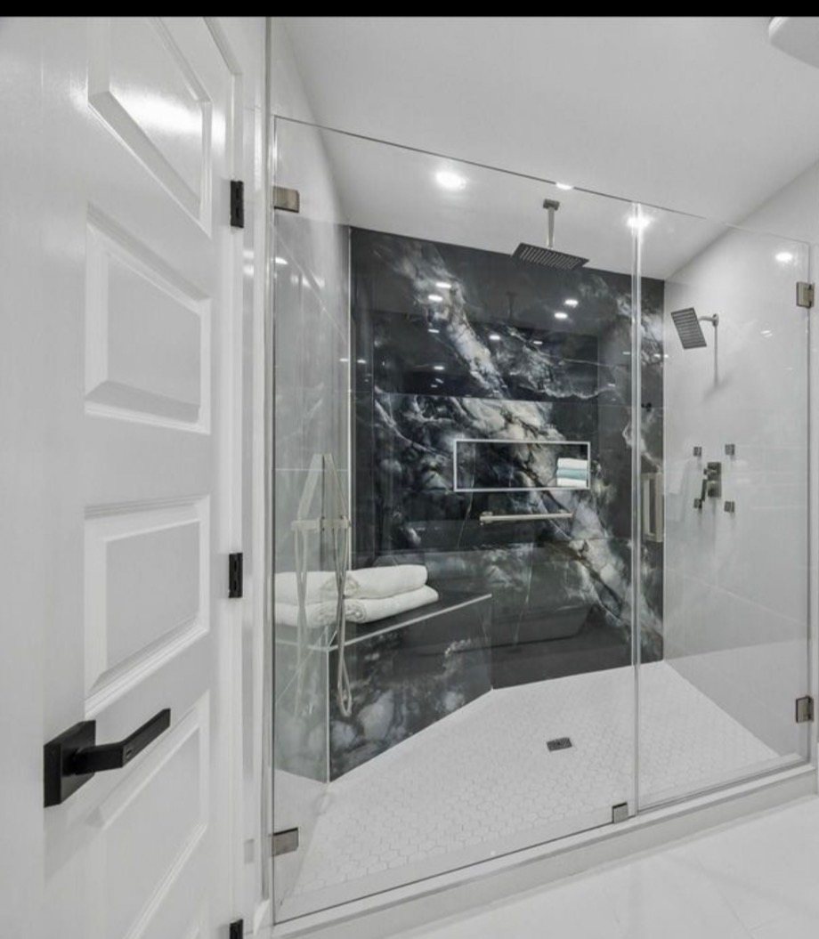 Walk-in shower with dramatic dark exotic stone accent wall and black fixtures