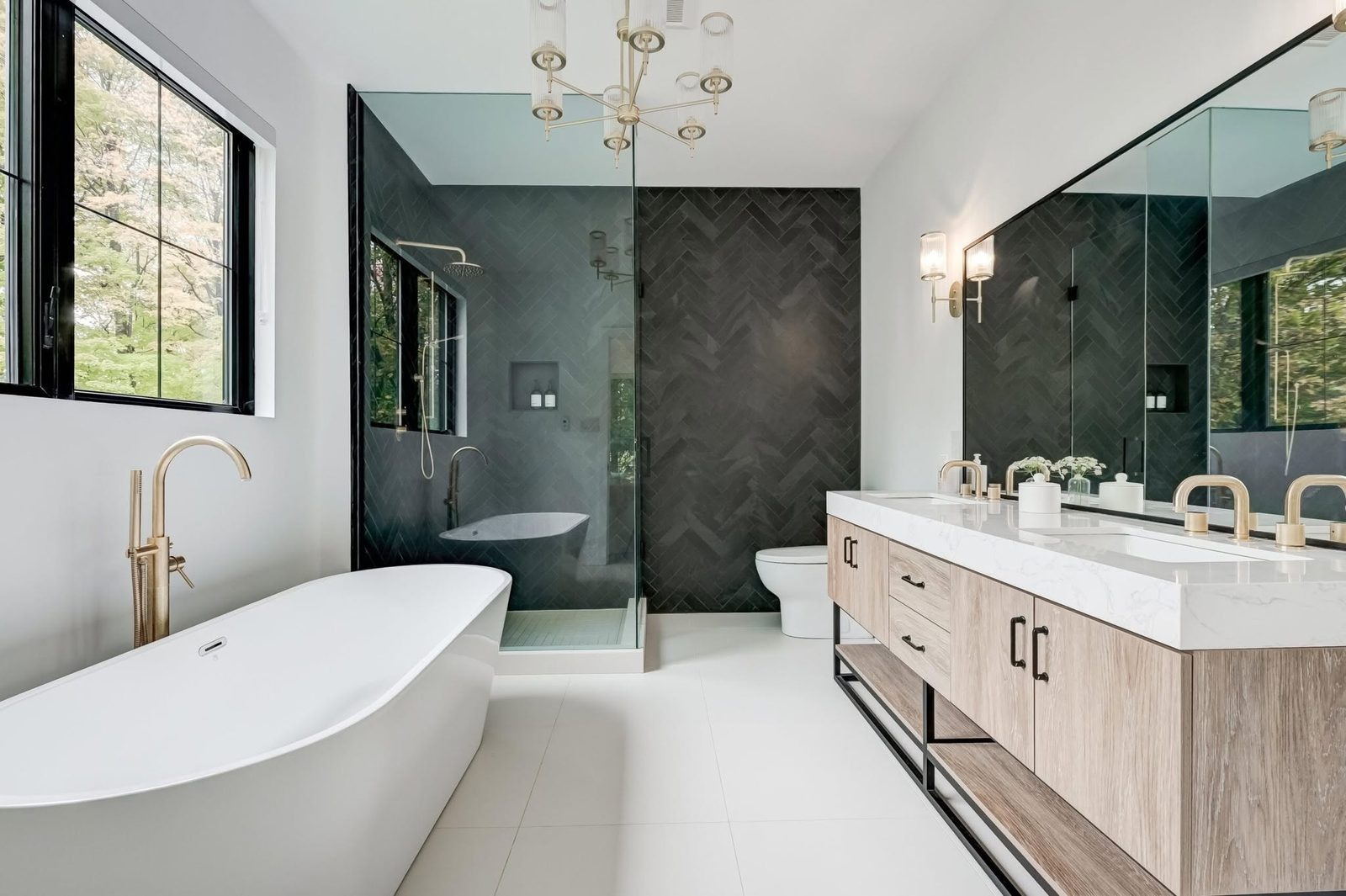 Luxury remodeled bathroom with freestanding tub, black herringbone tile, and brass fixtures by Trewick Custom Renovations in Houston