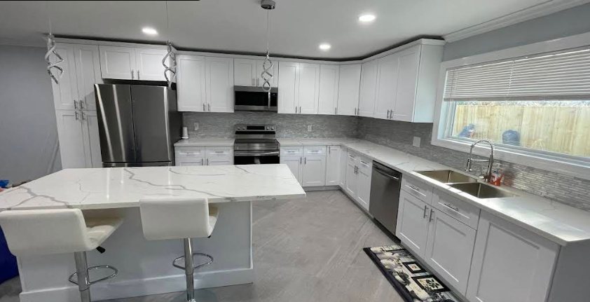 Modern kitchen with white shaker cabinets, quartz waterfall island, and stainless appliances