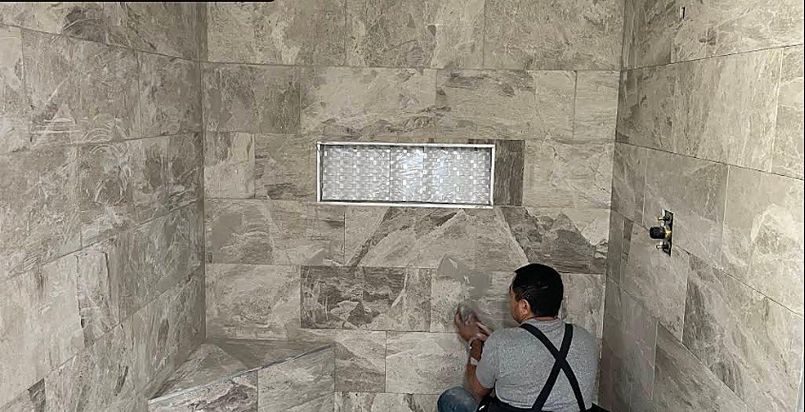 Trewick Custom Renovations craftsman installing marble tile in a walk-in shower